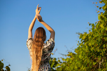 beautiful blonde girl with long curly hair.  femininity and sensuality.  photograph for advertising against the background of the sky and greenery