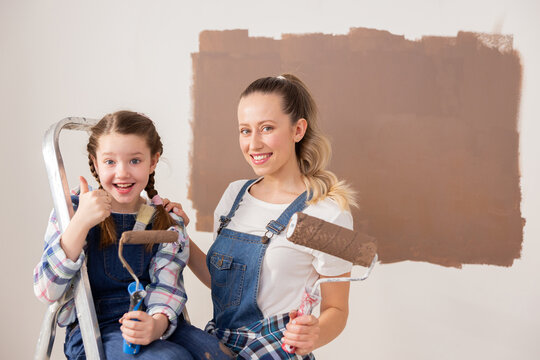 One grown woman and a little girl, dressed in denim, began the renovation. The child is very happy, because this experience is the first for her. She is showing super and holding a paint roller.