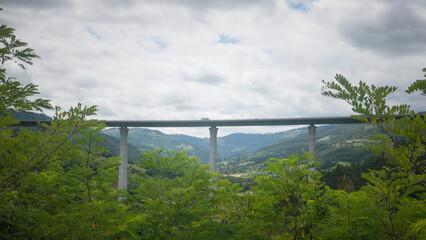 Viaducto de autopista con pilares de hormgón entre montes en valle de Asturias