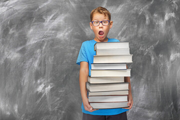 Boy carries a high stack of books - A lot of study material at school.