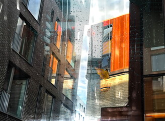 Rain in  city , Rainy drops and yellow leaves on window ,  view on  modern  buildings  architecture design blurred evening light  in city street  cold season  blurred light reflection on wet template 