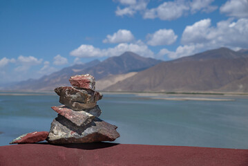 Mani stone pile in Tibet against tranquil lake