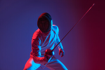 Male fencer with smallsword practicing fencing isolated on purple background in neon light. Sport, energy, skills, achievements - obrazy, fototapety, plakaty