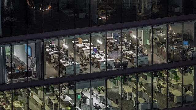 Big glowing windows in modern office buildings timelapse at night, in rows of windows light shines. Open space working places