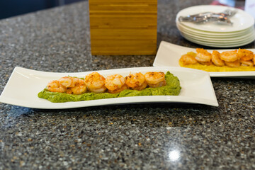 baked prawns on sweet potato puree on a platter.