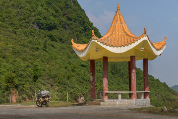 Yellow asian style pavilion located in green mountains