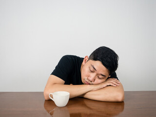 Sleepless man sitting sleep at table with coffee cup at morning