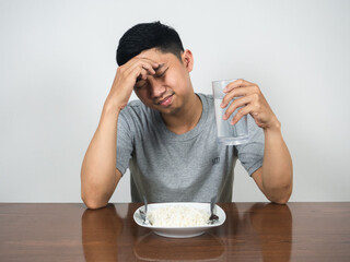 Asian man feels headache and sickness don't want to eat food on table