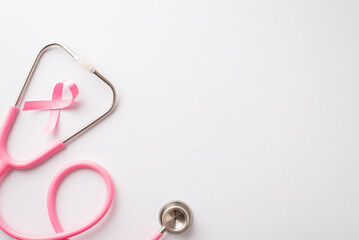 Breast cancer awareness concept. Top view photo of pink silk ribbon and stethoscope on isolated white background with copyspace