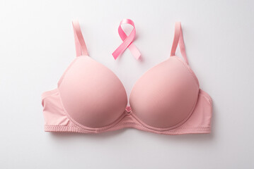 Breast cancer awareness concept. Top view photo of pink brassiere and pink ribbon on isolated white...