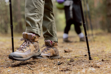 Close up of woman's rugged hiking boots and jeans on a leaf covered forest trail. Hiker in the...