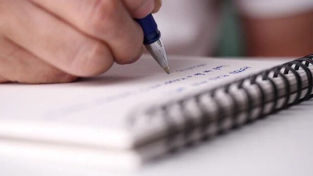 Concept of writing on paper, letter, pen, notepad, diary. Close up hand writing paper on notebook with blue pen to note, memo, list action plan at office or home desk, selective focus 4k resolution.