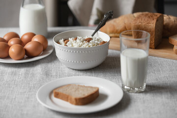 At home, in the kitchen, the table is covered with a linen tablecloth and there are natural and healthy products, milk and cottage cheese, bread and boiled chicken eggs on it
