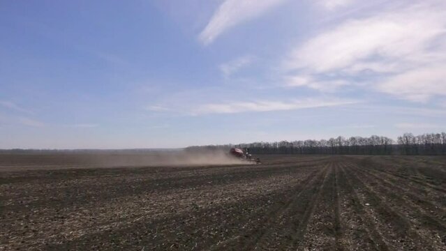 Tractor sowing seed on plowed field in Ukraine. Sowing seeds of corn and sunflower.