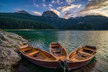 Obraz premium Three wooden boats in the Black Lake with Mount Durmitor and forest in the background in Montenegro