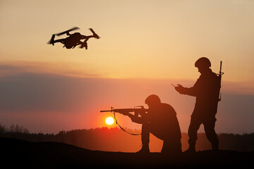 Obraz na płótnie Canvas Silhouettes of soldiers are using drone and laptop computer for scouting during military operation against the backdrop of a sunset. Greeting card for Veterans Day, Memorial Day, Independence Day.