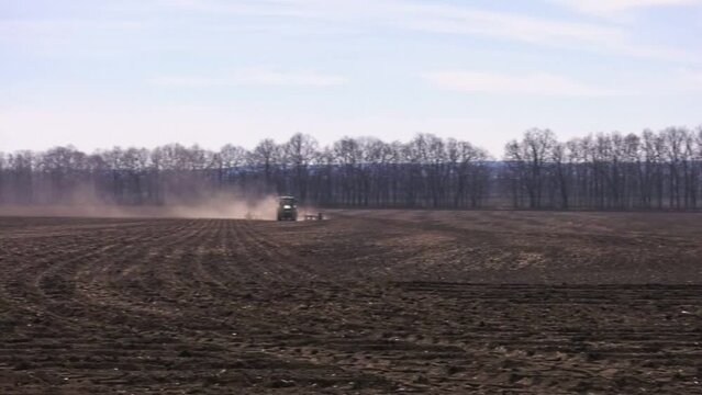 Tractor sowing seed on plowed field in Ukraine. Sowing seeds of corn and sunflower.