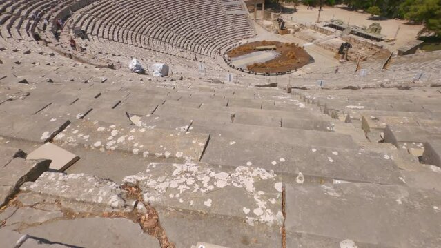 Day panning panoramic auditorium view with circular orchestra of the 4th Century BC Ancient Theater at the Asclepieion of Epidaurus in Greece.