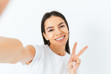 Cheerful brunette young woman making selfie showing two fingers