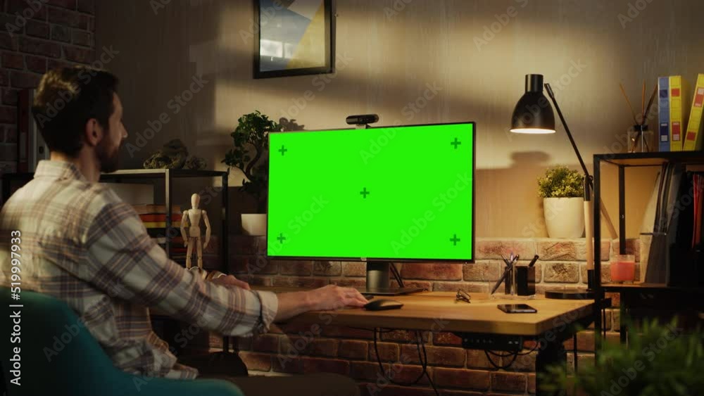 Poster Office Employee Working from Home, Talking on Video Call on Desktop Computer with Monitor with Green Screen Mock Up. Man Sitting in Living Room, Chatting Online with Friends and Family in the Evening.
