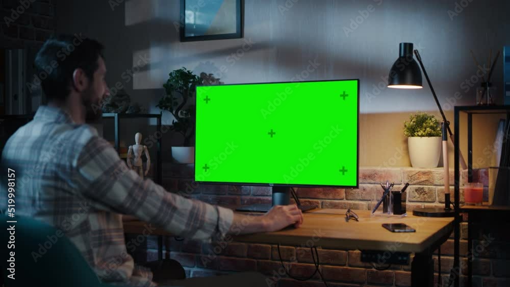 Poster Freelance Designer Working Remotely at Home on Desktop Computer with Green Screen Display. Creative Specialist Wearing Checkered Shirt. Static Shot with Chroma Key Placeholder for Playback Video.
