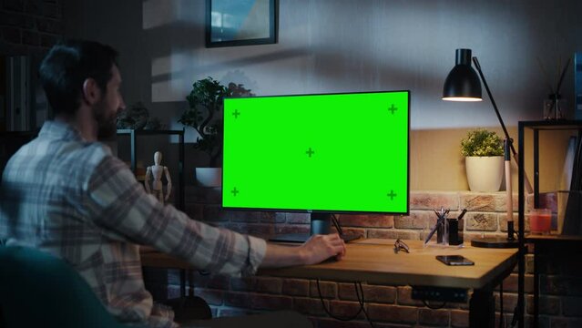 Freelance Designer Working Remotely at Home on Desktop Computer with Green Screen Display. Creative Specialist Wearing Checkered Shirt. Static Shot with Chroma Key Placeholder for Playback Video.
