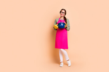 Full length photo of cheerful dreamy lady wear pink looking empty space ready cooking soup isolated beige color background