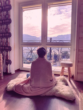 A woman meditates looking at purple mountains, the concept of a relaxing holiday in a house in the mountains