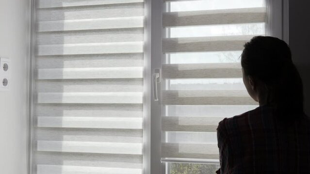 Woman checking cassette roller blinds on windows.