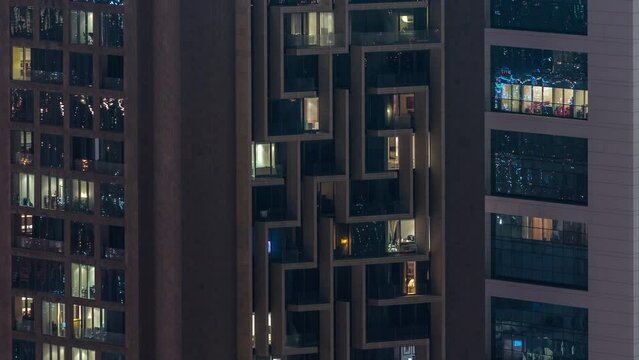 Windows in high-rise building exterior in the late evening with glowing and blinking interior lights on timelapse. Aerial top view