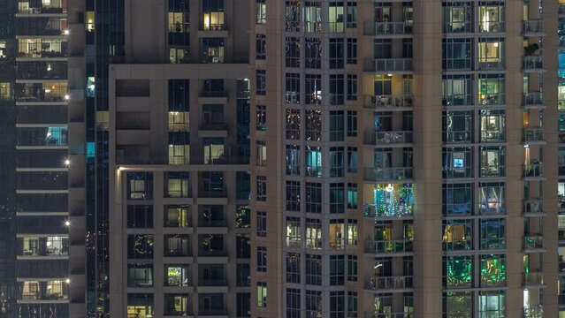 Big glowing windows in modern residential buildings timelapse at night, in rows of windows light shines.