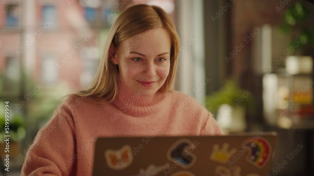 Aufkleber beautiful female working on laptop computer while sitting at a table in stylish cozy loft living roo