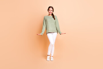 Fototapeta na wymiar Full length photo of sweet adorable girl dressed green pullover smiling isolated beige color background