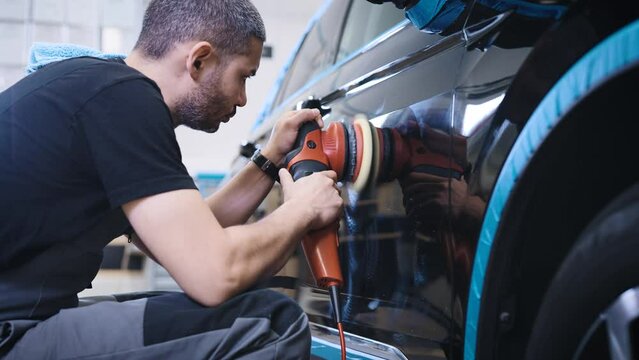 An experienced detailing studio worker polishing a car.