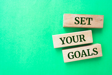 Set your goals words on wooden blocks on green background.