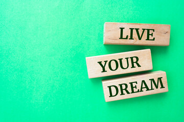 Live your dream words on wooden blocks on green background.