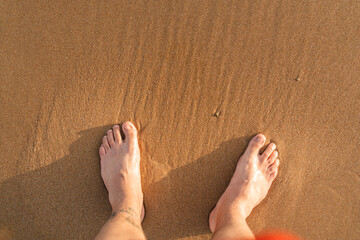 Pies visto desde arriba en la arena de una playa