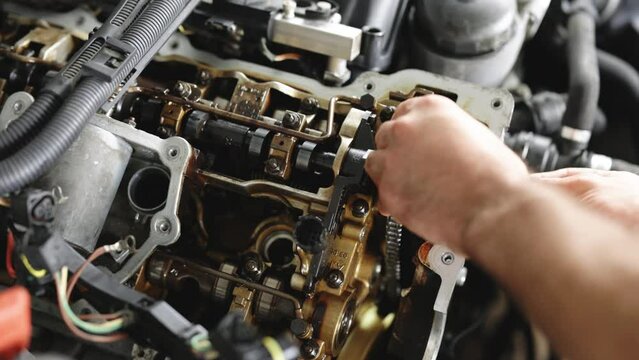 Auto mechanic working on car engine in mechanics garage. Repair service. Auto Car Mechanic Workshop Repair Car Engine. Car Mechanic Adjusts Front Housing Of Car Engine In Repair Shop