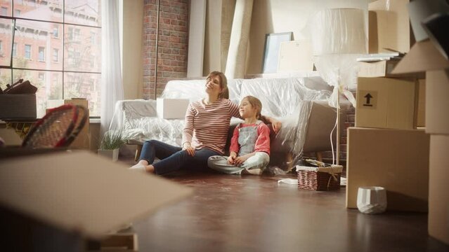 Moving Happy Mother and Daughter Talk, Sitting on a Living Room floor of their New Cozy Home. Cheerful Young Family, Dream, Imagine Good Times, Plan Apartment Decorations. Cardboard Boxes around. 