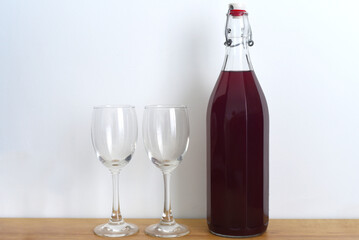 Homemade plum wine with glasses on white background