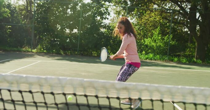 Video of happy biracial woman playing tennis on the court