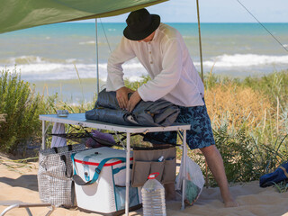 The man is putting together a tent. Summer vacation in a camping on the seashore.