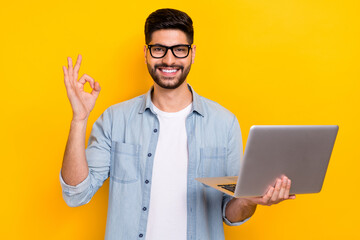 Photo of young business guy holding laptop showing okey sign buy advertisement google happy isolated on yellow color background