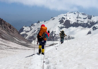 Fototapeta na wymiar Mountaineers rope descending Kazbek 5054m mountain with backpacks after successful summit ascending, Caucasus, Georgia