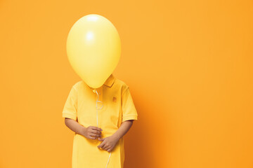 a little happy preschool boy happily plays with an orange ball standing on an orange background and...