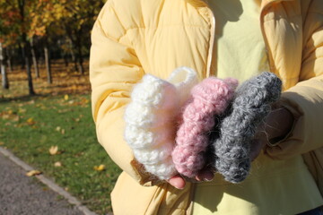 Headbands in the hand of an unrecognizable young girl on the street. Knitted hats. City Style. Fashion autumn-winter. Fashionable hats, headbands. Hobby.