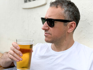 Middle aged man is drinking beer in a cafe or restaurant pub outdoor. Drinking alcohol. Candid....