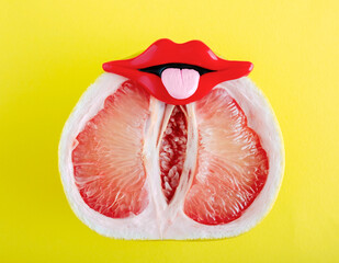 Fresh grapefruit with red lips mouth and tongue on yellow background. Creative art minimal poster. Sex concept.
