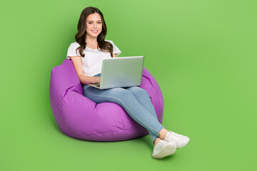 Photo of funny sweet lady wear white t-shirt sitting beanbag working device empty space isolated green color background