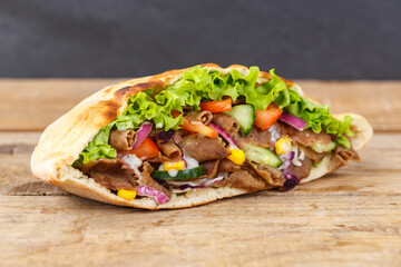 Döner Kebab Doner Kebap fast food in flatbread on a wooden board
